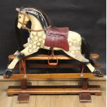 An antique dapple grey rocking horse, having glass eyes, leather bridle and saddle,