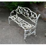 A Victorian cast iron branch form garden seat, detached arm. Height 85 cm, width 130 cm.