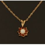 A 9 ct gold opal and garnet pendant, with fine 9 ct gold chain.