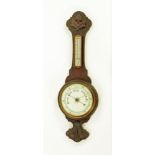 An Edwardian carved oak aneroid barometer with thermometer. Height 84 cm.