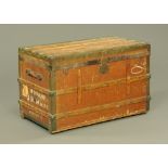 A vintage brass bound and canvas steamer trunk, with leather carrying handle.