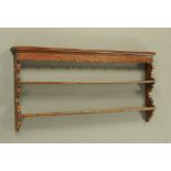 A Georgian oak plate rack, with shaped sides, moulded cornice and two open shelves.