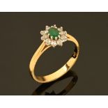 An 18 ct gold emerald and diamond cluster ring. Size O.
