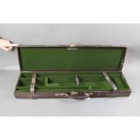 A leather shotgun motor case, opening to a green lined interior with space for 30" barrels.