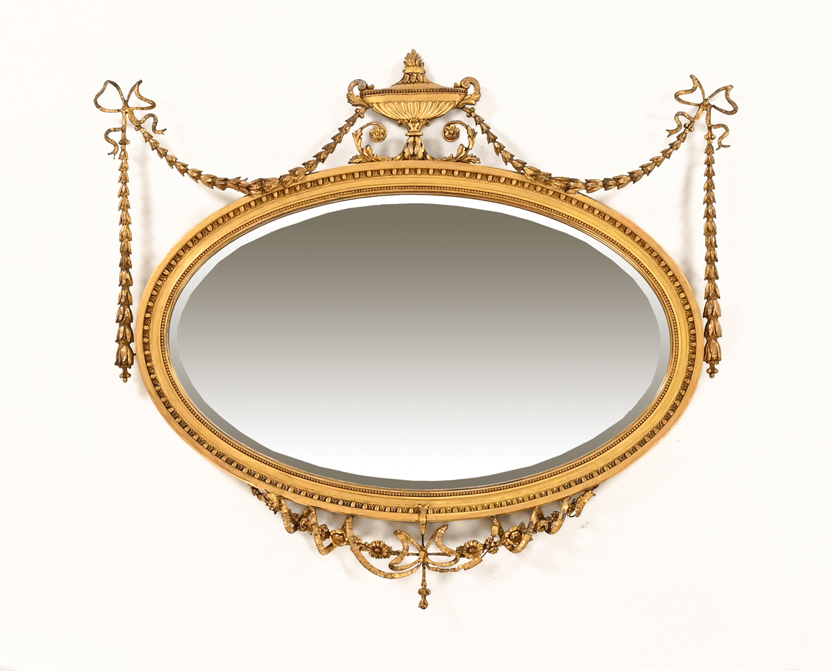 A late 19th/early 20th century Adam style oval giltwood and gesso framed bevelled glass mirror.