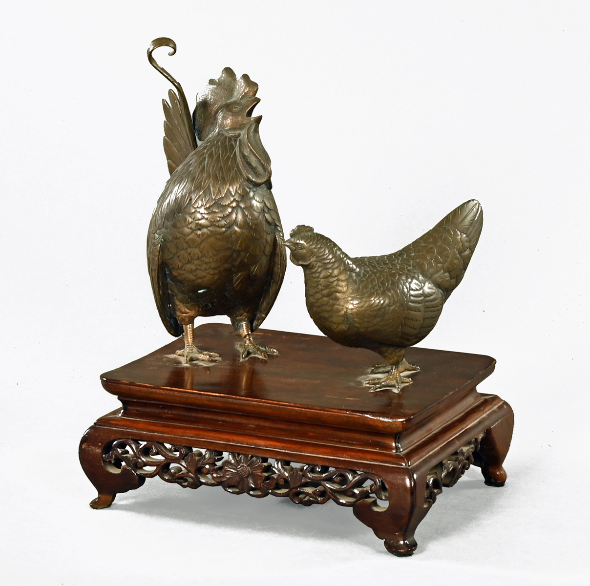 A Japanese bronze cockerel and hen, raised on a wooden base.