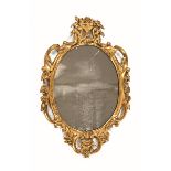 An antique giltwood and gesso wall mirror, with scrolling frame and with original mirror plate.