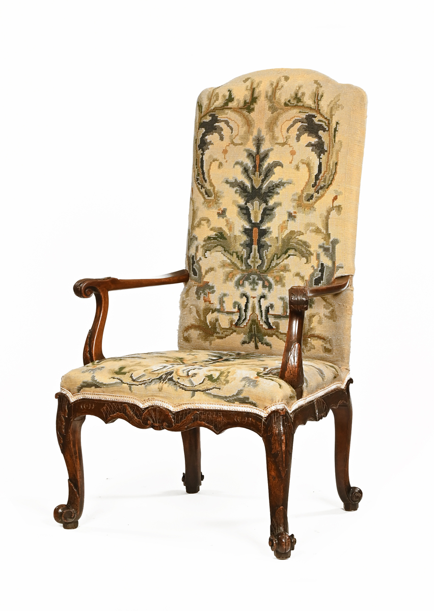 An 18th century armchair, with upholstered back and seat and with foliate carved outswept arms,