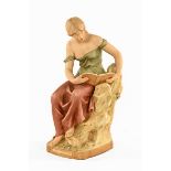 A Royal Dux figure of a seated female reading,