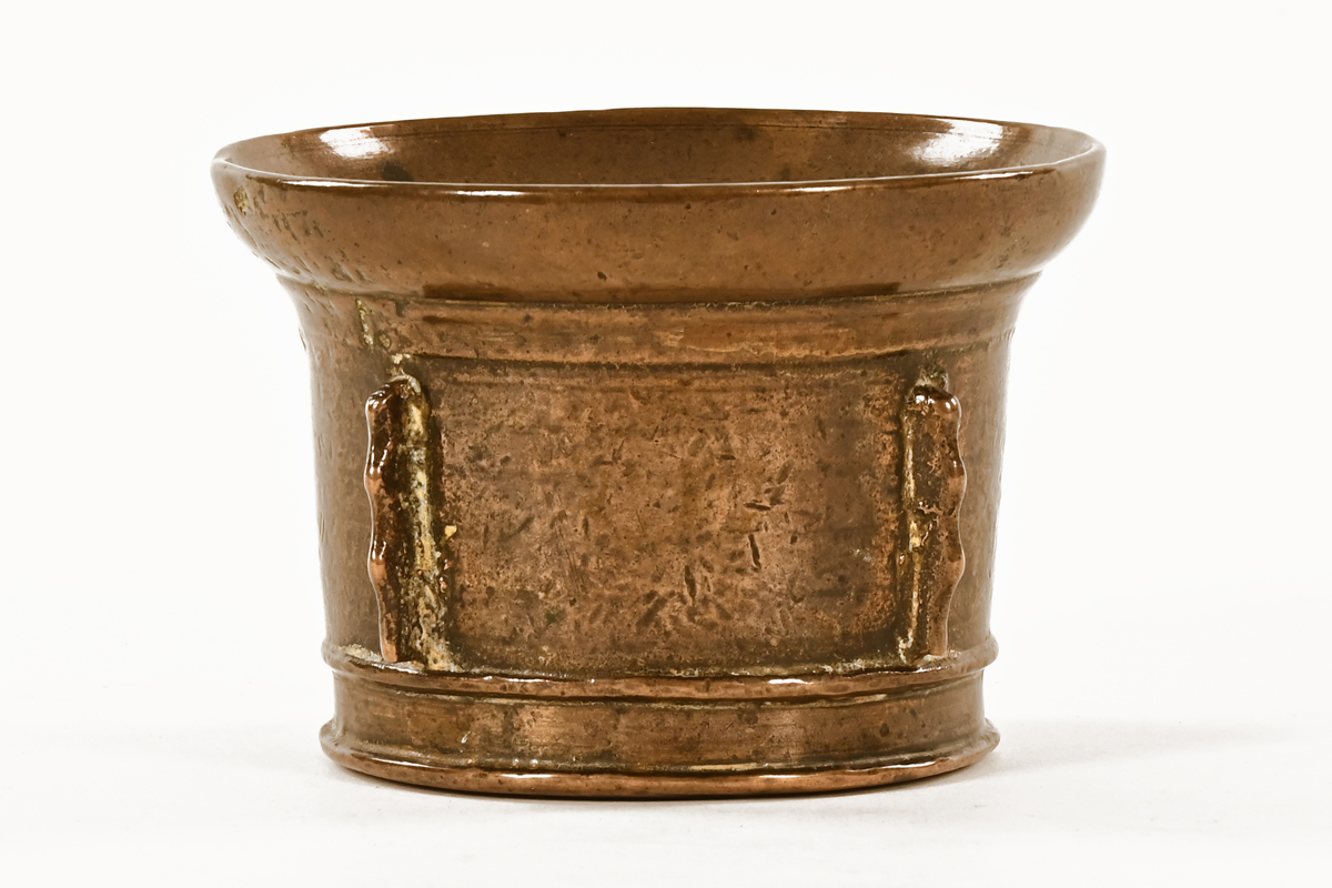 A small 17th century brass mortar, with flared rim and buttress decoration. 10 cm diameter.