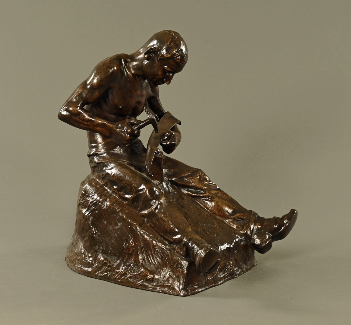 A Pohl bronze figure of a seated blacksmith fashioning a scythe blade. Height 50 cm.