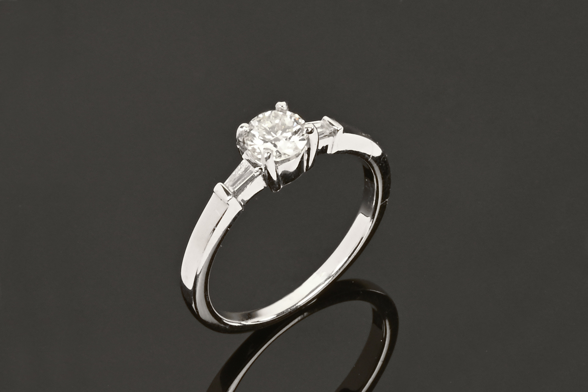 An 18 ct white gold ring set with a diamond to the centre and a baguette to each shoulder.