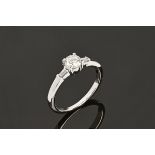 An 18 ct white gold ring set with a diamond to the centre and a baguette to each shoulder.