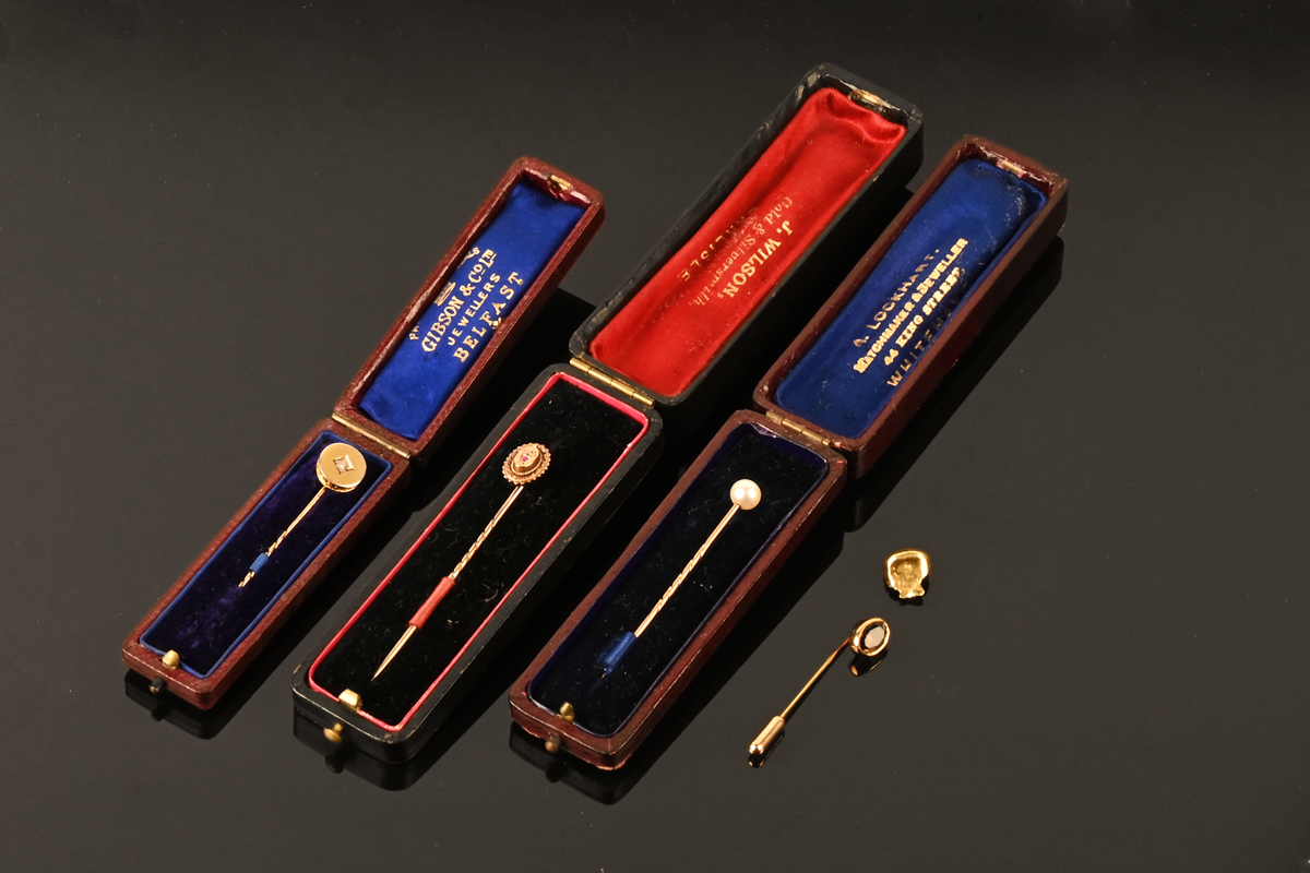 A gold coloured metal stick pin set with a single diamond, in Gibson & Co Jewellers Belfast case,