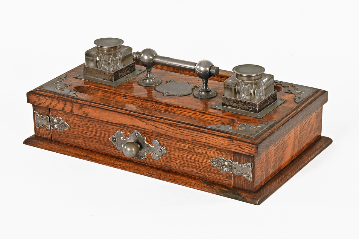 An Edwardian oak desk stand, with silver plated mounts, central drawer and two glass inkwells.