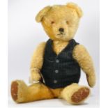 A large 1950's English Bear wearing a navy blue cord waistcoat. Golden mohair, amber and black