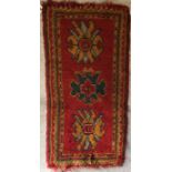 A Turkish rug, the central panel set with three stylised floral medallions on a red ground,