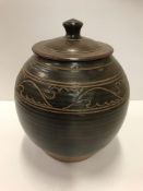 A studio pottery lidded pot with insisded foliate decoration to the shoulder,