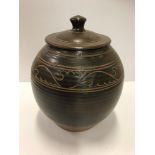 A studio pottery lidded pot with insisded foliate decoration to the shoulder,