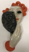 A Goldscheider glazed terracotta wall mask as a young woman holding a theatrical face mask,