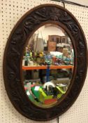 An early 20th Century oak framed wall mirror with carved stylised foliate and fish decoration,