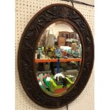 An early 20th Century oak framed wall mirror with carved stylised foliate and fish decoration,