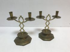 A pair of Arts & Crafts style brass twin branch candelabra, raised on octagonal stepped bases,