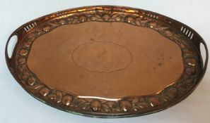 A Newlyn style copper twin-handled oval tray with pierced edge and embossed fruit decoration with