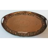 A Newlyn style copper twin-handled oval tray with pierced edge and embossed fruit decoration with