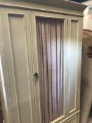 An early 20th Century painted single door wardrobe with chicken wire panel and fabric covered door