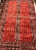 A Bokhara carpet, the central panel split into four, the red ground set with repeating design,