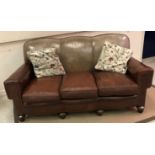 An early 20th Century brown leather upholstered three seat sofa with brass studded arms and triple