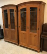 A pair of modern stained pine domed top part glazed two door cupboards or wardrobes with brass