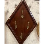 A set of four brass hat and coat hooks mounted on a mahogany lozenge panel with moulded edge,
