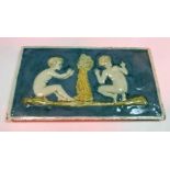 A Della Robbia rectangular tile depicting two children either side of a smoking fire 13 cm x 24 cm