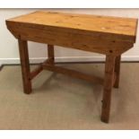 A modern pine work bench with plank top on square supports united by a centre stretcher 122.