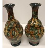 A pair of Doulton Lambeth faience ware vases, the brown ground set with floral decoration,