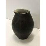 A Lucie Rie pouring vessel, with black glazed exterior and simple design,