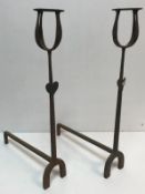 A pair of wrought iron fire dogs with muller holders and set with love heart decoration 70 cm high