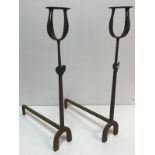 A pair of wrought iron fire dogs with muller holders and set with love heart decoration 70 cm high