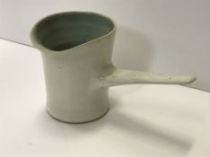 A Lucie Rie cream glazed pouring jug with side handle, with pale blue interior,