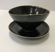 A Lucie Rie black glazed elliptical bowl and saucer, both bearing Lucie Rie marks,