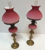 A pair of Victorian brass and cranberry glass oil lamps by Veritaslamp Works London,