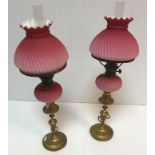 A pair of Victorian brass and cranberry glass oil lamps by Veritaslamp Works London,