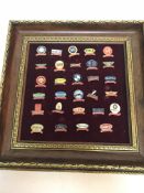 A framed display of 29 enamelled pin badges relating to various motor sport races to include