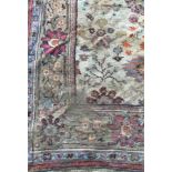 An Indian carpet, the central panel set with floral design on a cream ground,