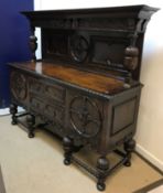 An oak sideboard in the 17th Century style, the raised back on reeded cup and cover supports,