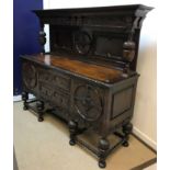An oak sideboard in the 17th Century style, the raised back on reeded cup and cover supports,