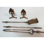 An Arts & Crafts style copper fire companion set comprising poker, shovel and tongs and fire dogs,