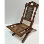 A Victorian child's folding caned campaign style chair with acanthus carved scrollwork top rail on